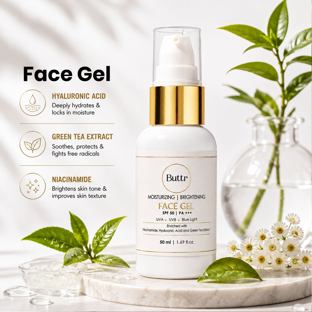 A bottle of Buttr Tr Face Gel SPF 30 with a white body and gold pump collar, styled on a marble tray with green leaves, white flowers, and glass droplets against a bright, softly lit background.
